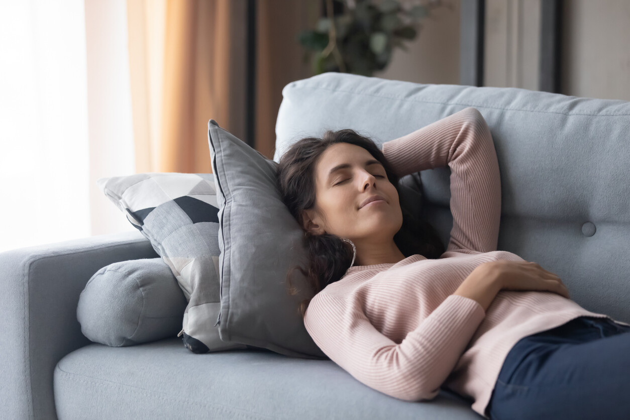 Person liegt entspannt auf dem Sofa und kommt bewusst zur Ruhe